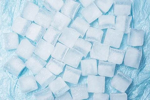 Frozen ice cubes for drinks arranged in a scattered pattern on a blue surface Foto stock