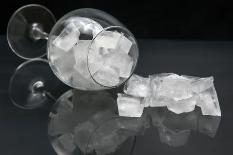 Frozen ice cubes in an empty wine glass on a dark background Stock Photos