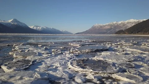 Frozen ice floating on the river surface and snow clad mountains at distance Stock Footage 104527899