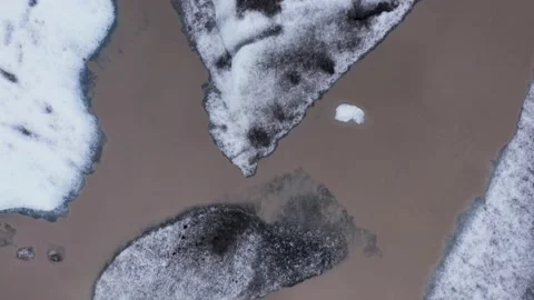 Frozen icebergs with black ash on surface floating in brown glacial lagoon 库存影片 205467104
