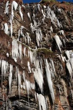 Frozen icicles on a cliff face Stock Photos