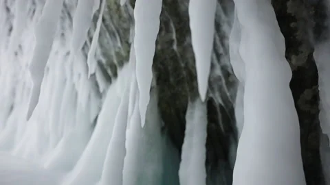 Frozen icicles, stalactites hang on ceiling in cave. White ice spikes cover wall Stock Footage 166566953