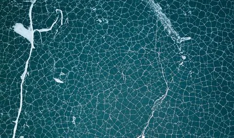 Frozen lake with abstract pattern of ice cracks. Beautiful winter background Stock Photos