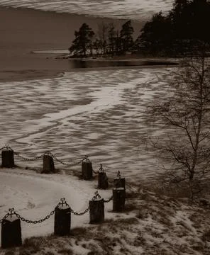 Frozen lake and stone posts with chain in sepia, Sweden Foto stock