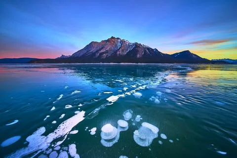 Frozen Lake Methane Bubbles and Mountain at Sunset in Winter Foto stock