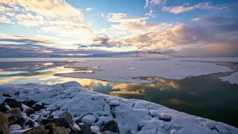 Frozen lake reflecting sunset clouds and mountains in winter. Stock Footage 341068561