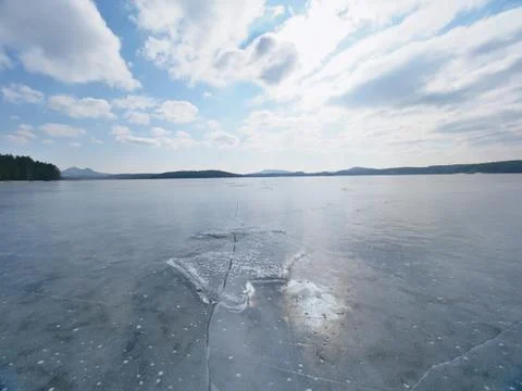 Frozen lake. Reflection of sun rays in flat ice on the lake. Air bubbles Stock Photos
