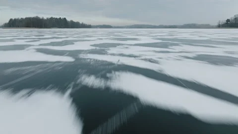 Frozen Lake with snow patterns from low wide angle fast flying Mavic 3 Stock Footage 169130024