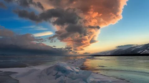 Frozen Lake Sunset Landscape with Dramatic Clouds and Mountains Stock Photos