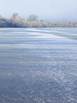 A frozen lake with trees in the background Stock Photos