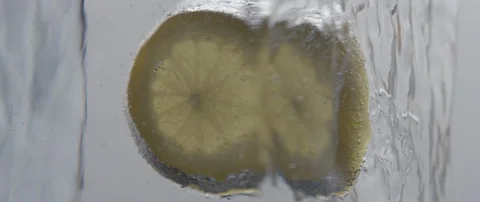 A frozen lemon slice rotates in an ice cube on white background Stock Footage 106006594