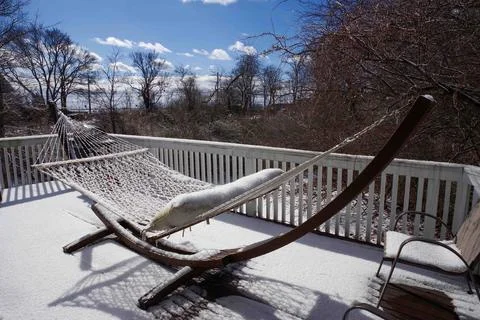 Frozen macrame hammock on a snow covered residential deck facing sun Stock Photos
