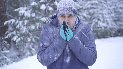 Frozen man on the background of the snow uses a smartphone, talking on the phone Stock Footage 101135105