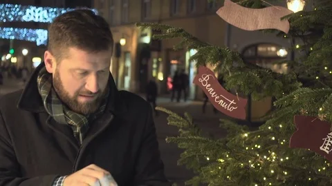 Frozen man browsing tablet, warming up next to christmas tree, night, steadycam 库存影片 72782149