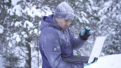Frozen man in cold winter enjoys a laptop Stock Footage 101135444