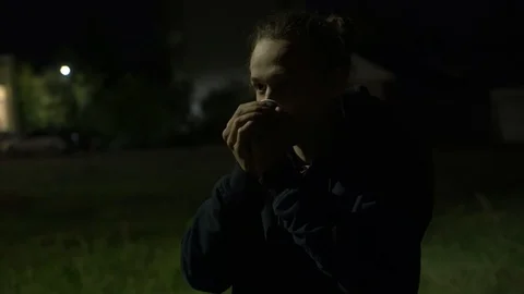 Frozen man drinking hot coffee on the streeet at night, 4k footage 库存影片 98878940