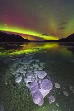 Frozen Methane Bubbles Northern Lights and Mountain Silhouette Reflected on.. Stock Photos