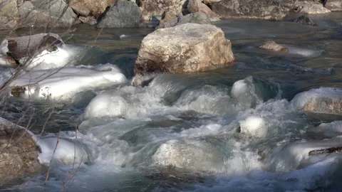 Frozen mountain river flowing with icy water Stock Footage 325695884