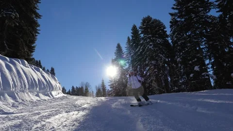 Frozen mountain slope illuminated by sunlight as skier speeds downhill Stock Footage 325792941