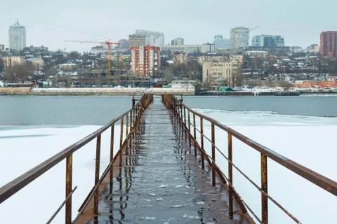 Frozen old pier at river side in winter time. Stock Photos