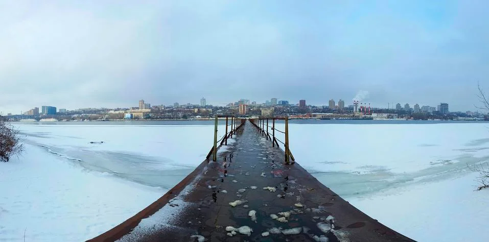 Frozen old pier at river side in winter time. Stock Photos