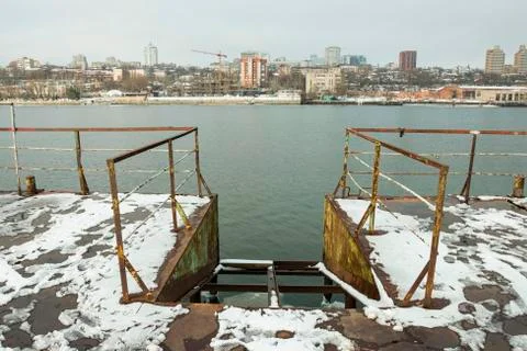Frozen old pier at river side in winter time. Stock Photos