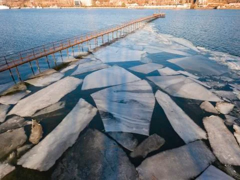 Frozen old pier at river side in winter time. Stock Photos