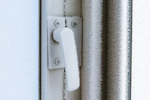 Frozen plastic window hardware lock. Frozen window. Stock Photos