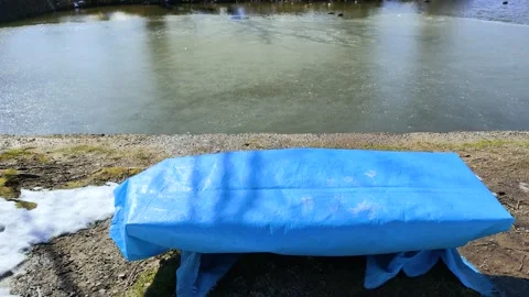 A frozen pond and a bench covered with a blue tarp Stock Footage 322040167