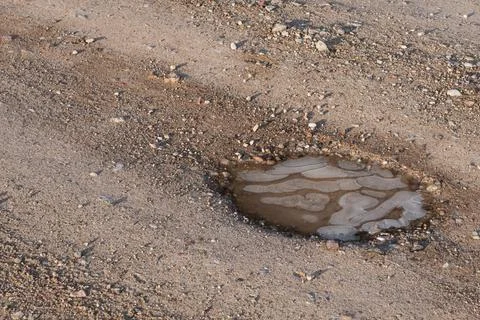 Frozen puddle with ice air bubbles. Slippery countryside road. Stock Photos