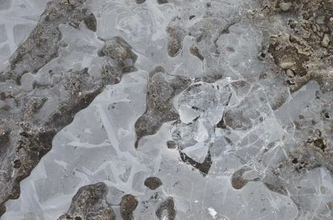 Frozen puddle reveals intricate patterns and textures during winter Stock Photos