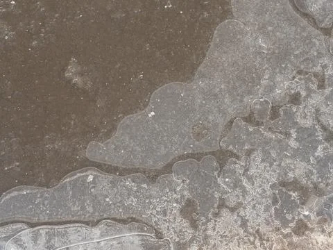 Frozen puddle on the road. close-up. First ice. Slippery Foto stock