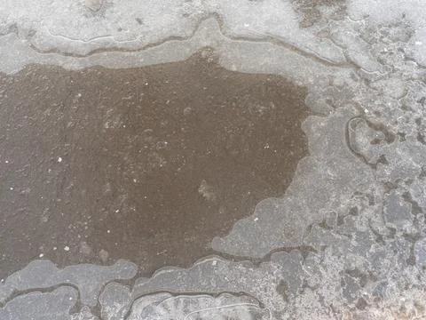 Frozen puddle on the road. close-up. First ice. Slippery Foto stock