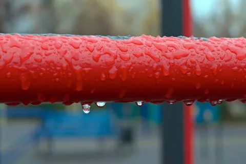 Frozen raindrops on red pipe close up on blurred background focus in center Stock Photos