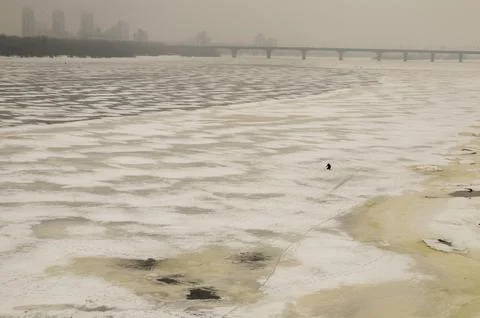 Frozen river with bridge and distant city skyline Stock Photos