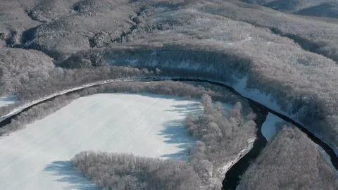 A frozen river flows between the trees covered with white snow. Stock Footage 169564401