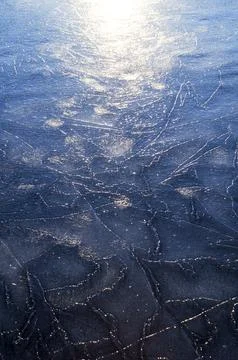 Frozen river. Sun rays on ice. Silver ice texture. Stock Photos