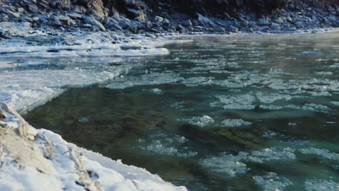 Frozen river surrounded by snow and ice in winter, sculpted by wind and wave Stock Footage 268605403
