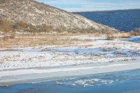 Frozen river winds through a snowy valley 库存照片