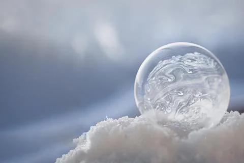 Frozen soap bubble with a beautiful pattern on the snow close-up on a blurry Stock Photos