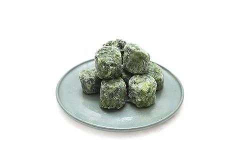Frozen spinach cubes portion on a ceramic plate, isolated on white 库存照片