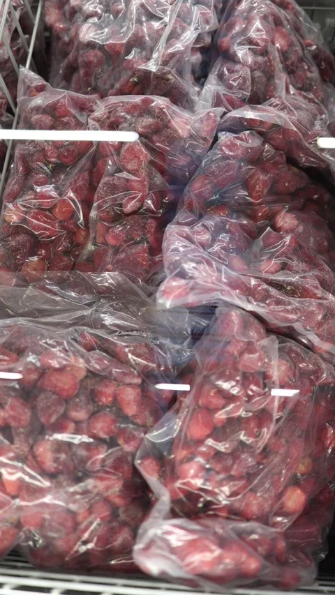 Frozen strawberries packed in clear bags and stacked in supermarket freezer Stock Footage 345978080