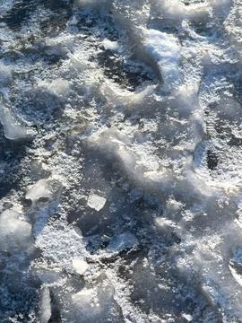 Frozen surface shows cracked ice with snow patches Fotos Stock