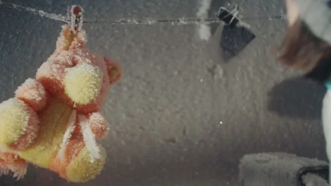 Frozen teddy discovered by child. Child uncovers frostcoated plush toy hanging Stock Footage 346474630