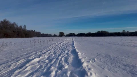 Frozen Trail With Deep Impressions Stretching Toward Distant Trees Beneath Stock Footage 327051084