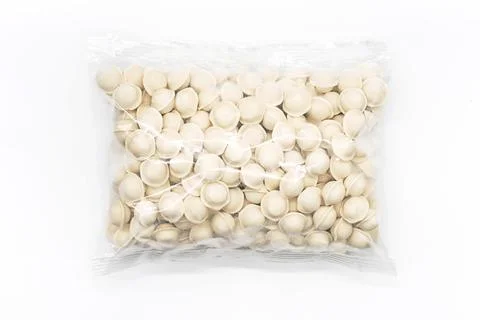 Frozen uncooked dumplings in plastic bag on white. Semi-finished product pelm Stock Photos