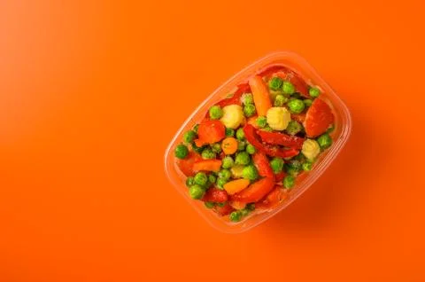 Frozen vegetables corn, red pepper, peas, carrots, tomatoes in plastic tray on Stock Photos