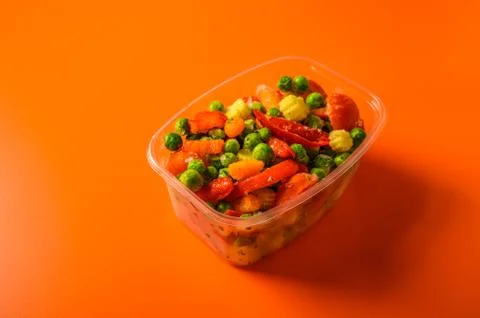 Frozen vegetables corn, red pepper, peas, carrots, tomatoes in plastic tray on Stock Photos