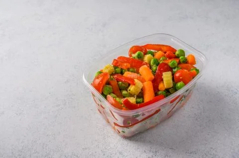 Frozen vegetables corn, red pepper, peas, carrots, tomatoes in plastic tray on Stock Photos