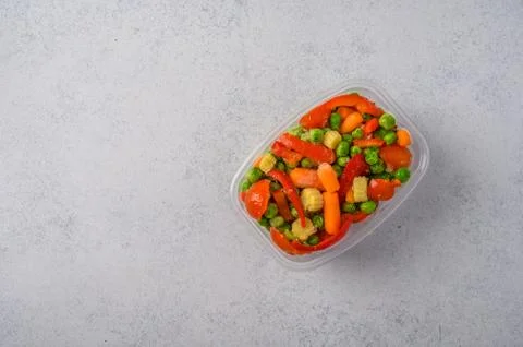 Frozen vegetables corn, red pepper, peas, carrots, tomatoes in plastic tray on Stock Photos